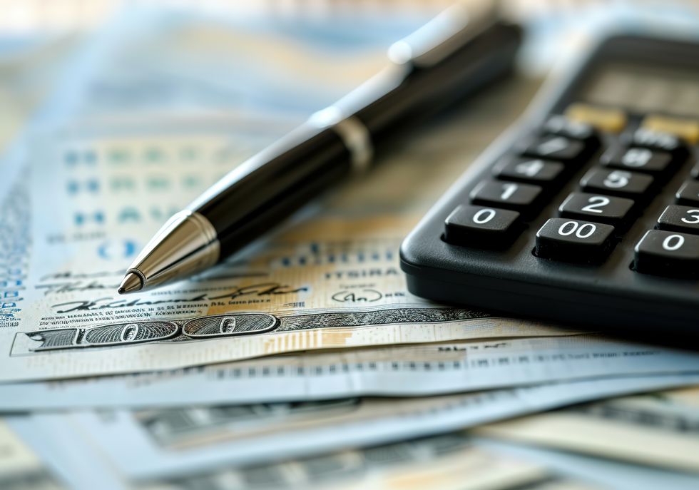 Close up on cash, a pen, and a calculator being used to record expenses